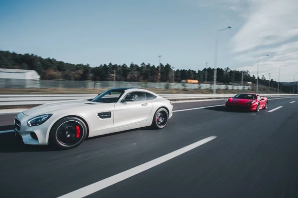 Carro esporte de luxo branco com luzes amarelas condução de alta velocidade e corrida com carro vermelho — Fotografia de Stock