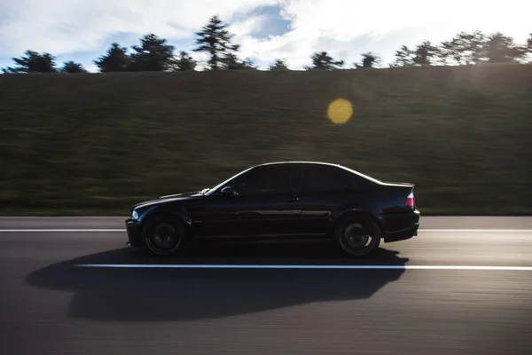 Voiture sport de luxe noire conduite à grande vitesse dans le noir de la soirée — Photo