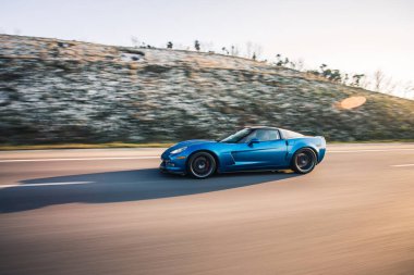 Dağ yolunda mavi marka spor model bir araba.