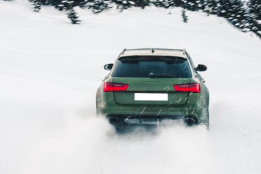 Yeşil off-road aracı. Kırmızı ışıkları olan. Ormana, karın üstüne park etmiş.