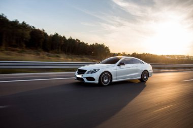 Güneşin altında beyaz birinci sınıf sedan araba