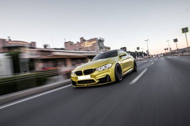Alacakaranlıkta binaların arasında sarı spor araba sürüşü