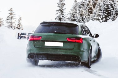 Yeşil off-road aracı karda orman yolunda dalıyor.