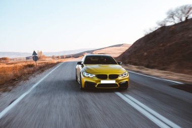 Yeşil lüks sedan araba yüksek hızla dağları aşıyor.
