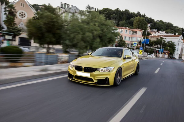 Conducir coche deportivo amarillo en la carretera de la ciudad en el tiempo del atardecer, vista frontal — Foto de Stock