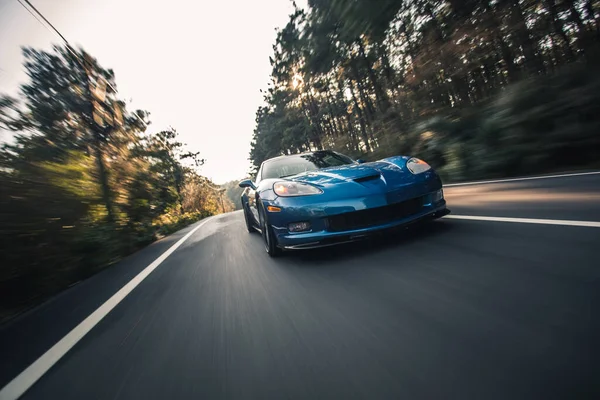 森林路上的蓝色品牌运动车型车速测试 — 图库照片