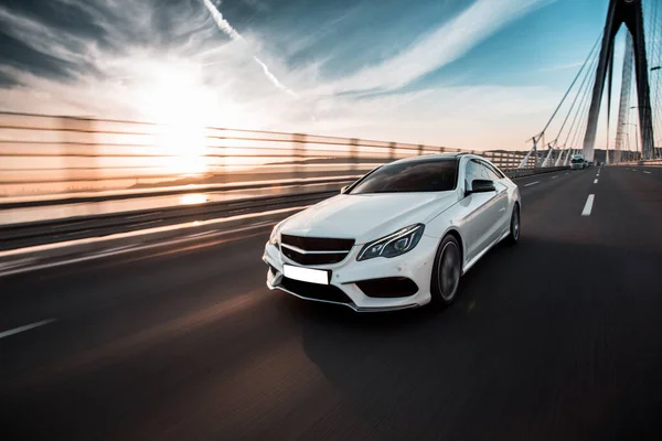 Beyaz birinci sınıf sedan araba köprüden geçen otobanda gidiyor.