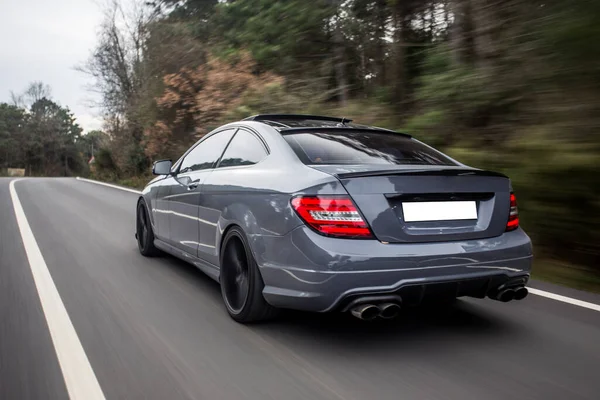 Cabriolet blu con luci rosse allo xeno sulla strada forestale, vista posteriore — Foto Stock