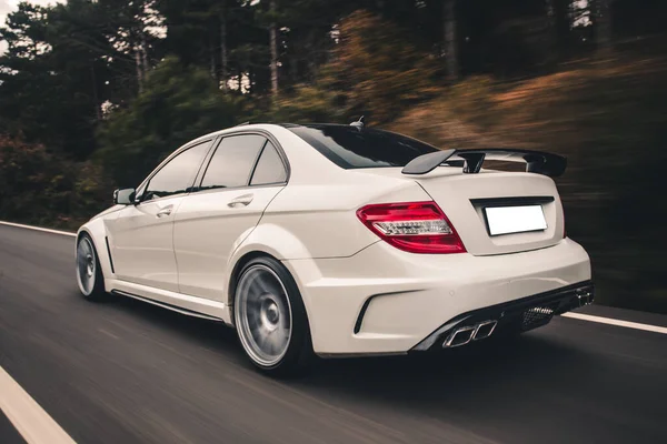 White sedan with red lights on the forest road, view from behind — Stock Photo, Image