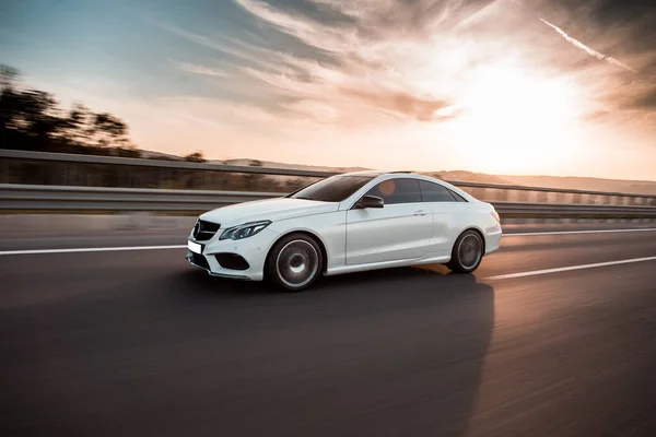 Günbatımında mavi gökyüzünün altında beyaz lüks bir araba.