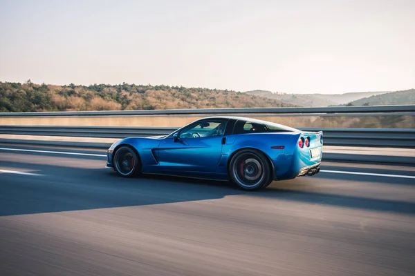 Coche deportivo de lujo azul en la autopista, conducción de alta velocidad, vista desde el perfil — Foto de Stock