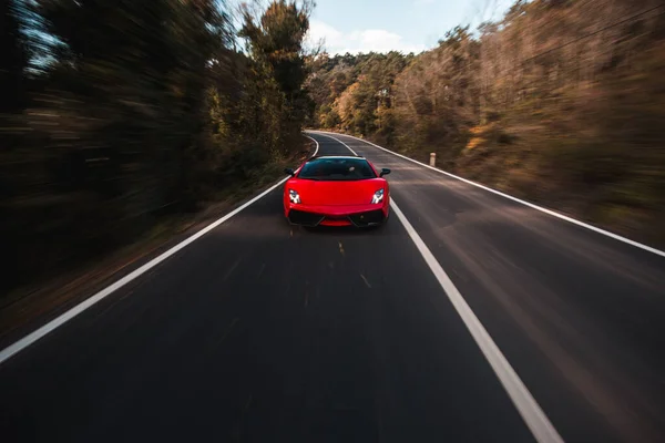 Super modèle de voiture rouge dans l'obscurité sur la forêt, la conduite droite — Photo