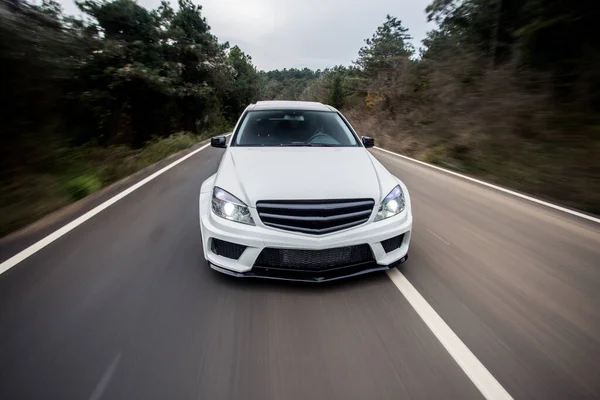 White offroader with white xenon lights, forest drive in the evening across trees, front lights on — Stock Photo, Image