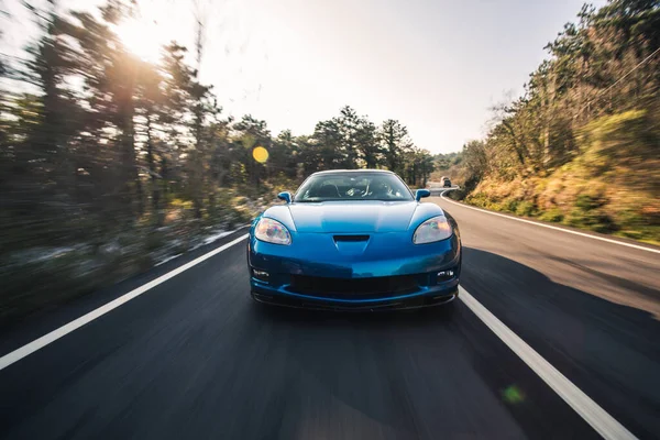 Teste de velocidade do carro modelo esporte marca azul na estrada através da floresta verde — Fotografia de Stock