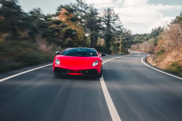 Voiture sport de luxe rouge sur la route, vue de face sur la forêt — Photo