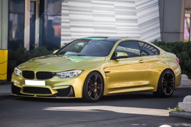 Sarı spor model araba, ön tampon ve ksenon ışıkları bir binanın önünde.