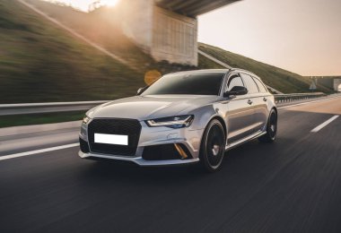 Gümüş renkli hatchback yolda, ön tarafta, köprünün altında