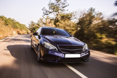 Orman yolunda siyah lüks bir sedan.