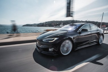 Siyah lüks araba deniz kenarında sürüyor.