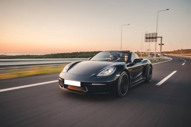 Siyah spor sedan Cabriolet köprüde, alacakaranlıkta yüksek hız sürücüsü