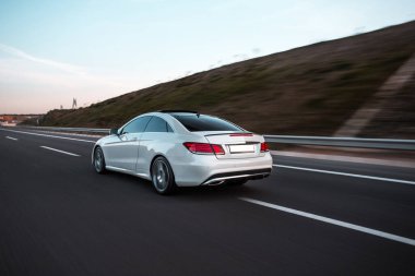 Kırmızı ksenon ışıklarıyla otoyolda beyaz birinci sınıf sedan araba sürüyor.