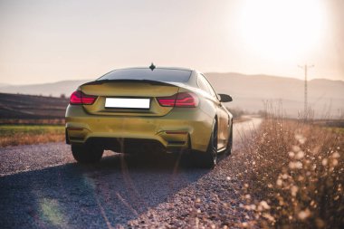 Yolda kırmızı ksenon ışıkları olan yeşil bir sedan araba.