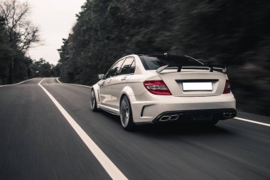 Orman yolunda kırmızı ışıkları olan beyaz sedan sağa dönüyor.