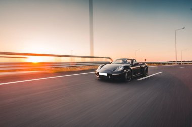 Otobanda siyah spor sedan Cabriolet, günbatımında yüksek hızlı sürüş.