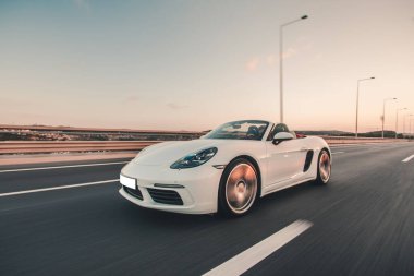 Beyaz lüks model araba tarlalarda otobanda sürüyor.