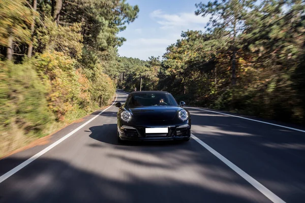 Черная супермодель седана на лесной дороге едет прямо — стоковое фото