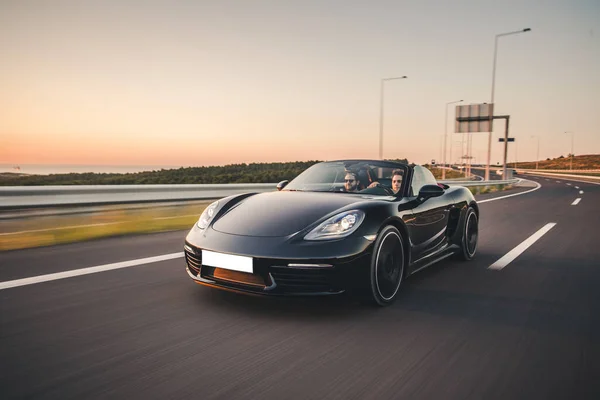 Zwarte sport sedan cabriolet over de brug, hoge snelheid rijden in de schemering tijd — Stockfoto