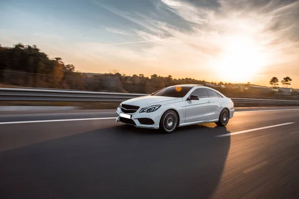 Otoyolda beyaz birinci sınıf sedan araba sürüyor.