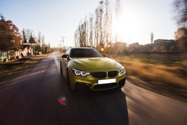 Sarı renkli hatchback ormanda yolda gidiyor, ön manzara