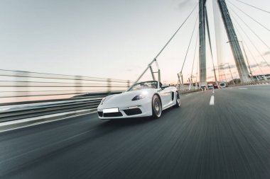 Köprünün üzerinde beyaz bir süper model araba var.
