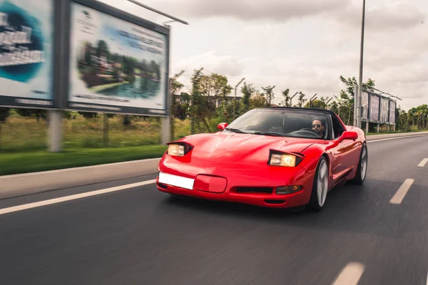 Carro esporte de luxo vermelho na autobahn com comerciais ao redor — Fotografia de Stock