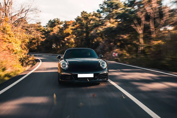 Černá super model sedan auto na lesní cestě v podzimním čase — Stock fotografie
