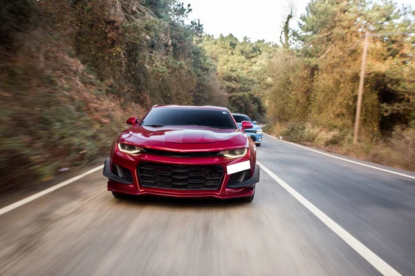 Voiture de sport rouge avec pare-chocs noirs dans la forêt — Photo