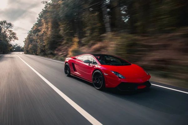 Ormanın karanlığında kırmızı süper model araba, hız sürücüsü. — Stok fotoğraf