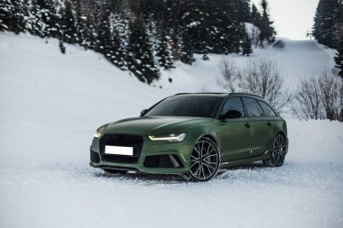 Yeşil spor model off roader karlı bir ormanda meşe ağaçları arasında, ön manzara