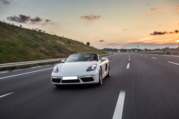 Coche cabriolet modelo super blanco conduciendo en la carretera al atardecer — Foto de Stock