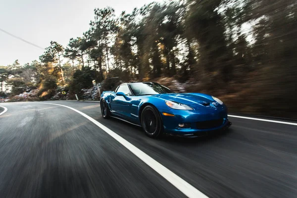 Kék márka sport modell autó sebesség teszt az erdei úton napkelte előtt — Stock Fotó