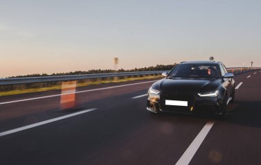 Otobanda güneşli bir havada siyah spor model taksi.