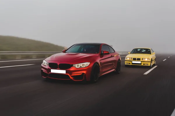 Vermelho e amarelo sedans esporte correndo em um clima nebuloso — Fotografia de Stock