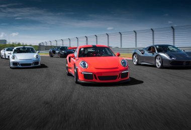 Kırmızı, siyah ve beyaz spor arabalar otoyolda diğer arabalarla yarışıyor.