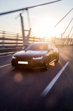 Günışığı altındaki modern köprünün tasarımında siyah sedan araba.