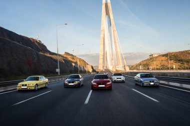 Köprüde çok sayıda spor araba yarışıyor.