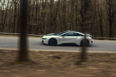 Yeşil orman ağaçlarının arasında beyaz spor araba.