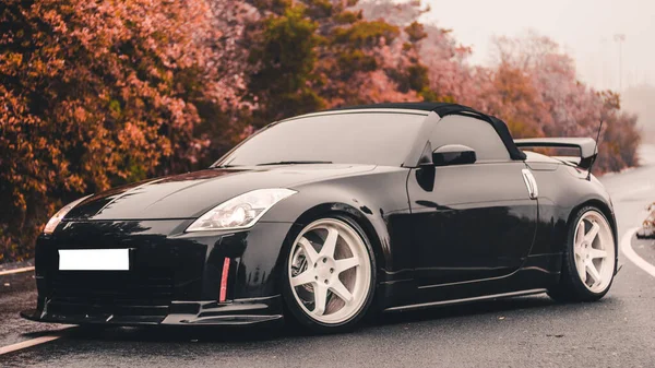 Carro esporte de design preto estacionado na floresta de outono — Fotografia de Stock