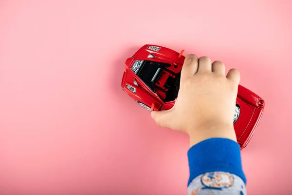 Kis piros autó játék egy gyereknek, egy gyerek játszik vele — Stock Fotó