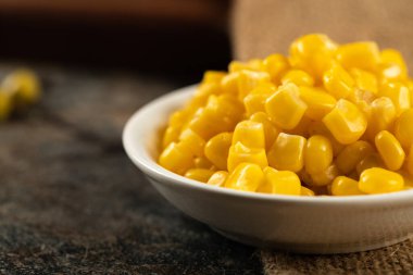 Tahta masadaki beyaz bir tabakta mısır tohumları.